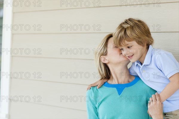 Caucasian mother kissing son on patio