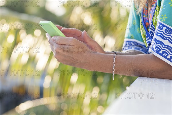 Hispanic woman using cell phone outdoors