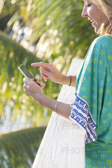 Hispanic woman using cell phone on patio