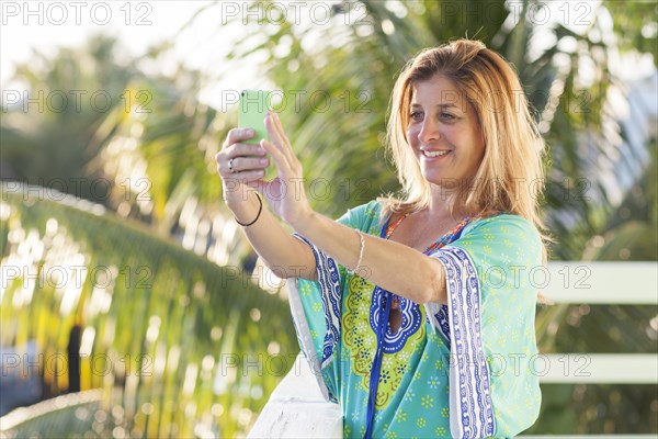 Hispanic woman taking selfie with cell phone on patio