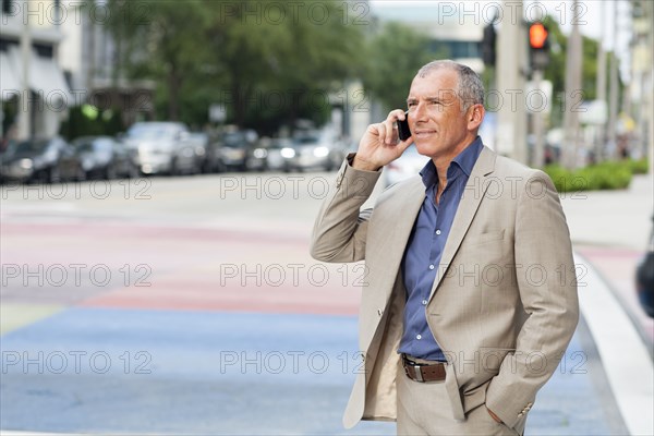 Caucasian businessman talking on cell phone at crosswalk