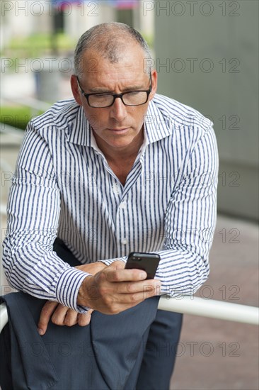 Caucasian businessman using cell phone at banister