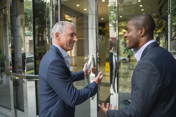 Businessman opening office door for colleague