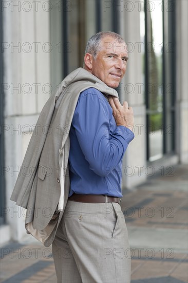 Caucasian businessman carrying jacket on city sidewalk