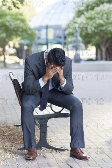 Frustrated Indian businessman sitting on bench