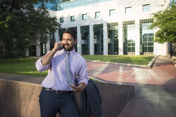 Indian businessman talking on cell phone outside office building