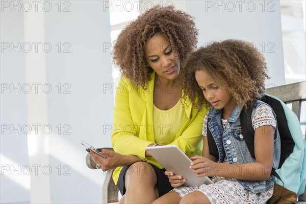 Mixed race mother and daughter using digital tablet