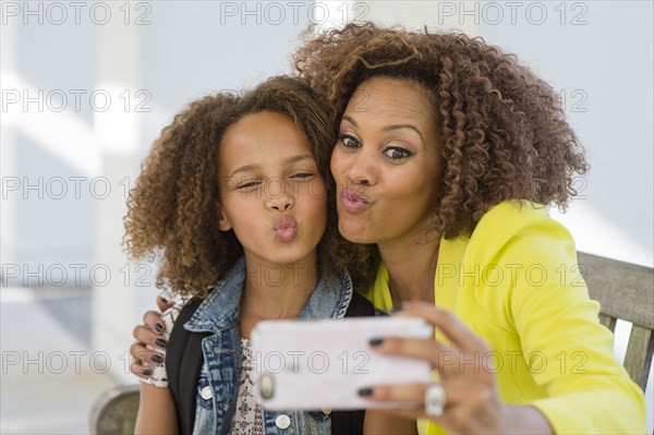 Mixed race mother and daughter taking selfie