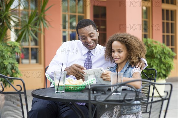 Father and daughter eating at outdoor restaurant table