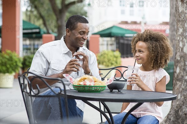 Father and daughter eating at outdoor restaurant table