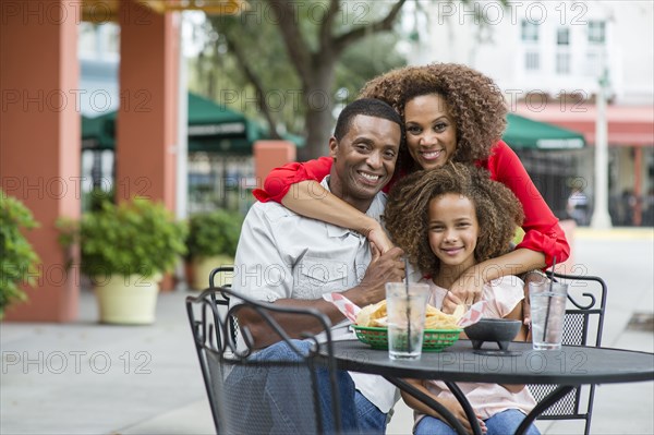 Family smiling at outdoor restaurant table