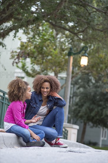 Mixed race mother and daughter sitting outdoors