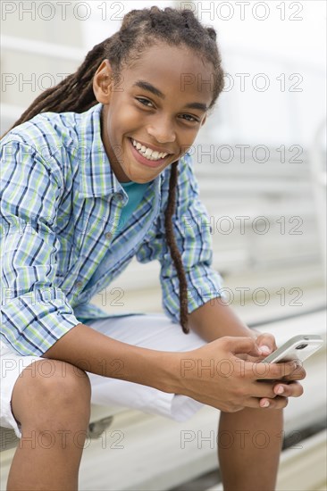 Mixed race boy using cell phone outdoors