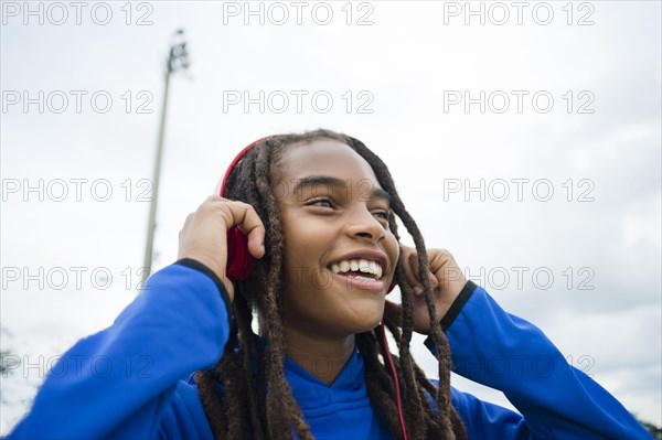 Mixed race boy listening to headphones outdoors