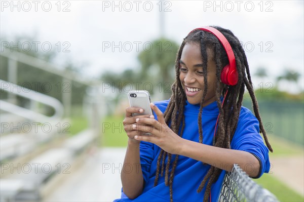 Mixed race boy using cell phone on bleachers