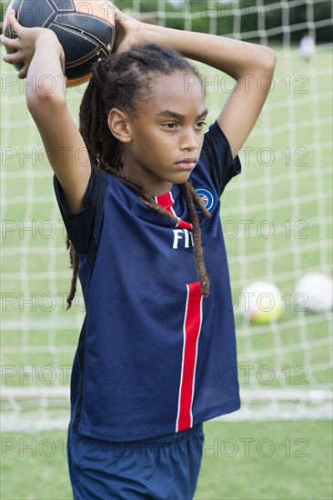 Mixed race boy throwing soccer ball on field