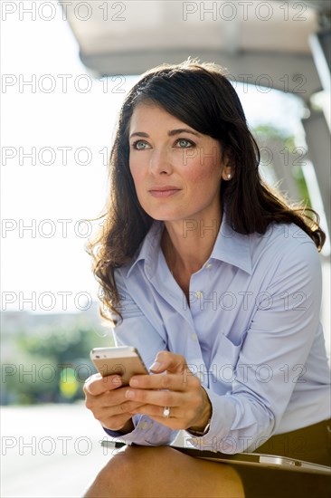 Caucasian businesswoman using cell phone at bus stop