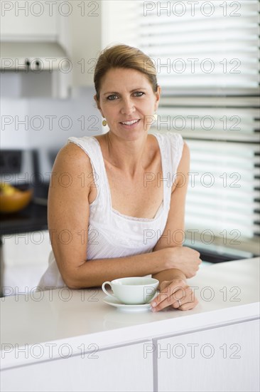 Caucasian woman drinking coffee in kitchen