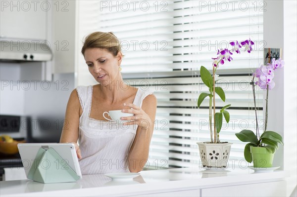 Caucasian woman using digital tablet in kitchen