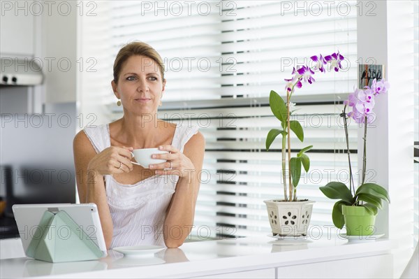 Caucasian woman drinking coffee in kitchen