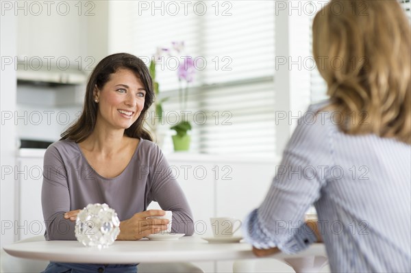 Caucasian women drinking coffee in kitchen