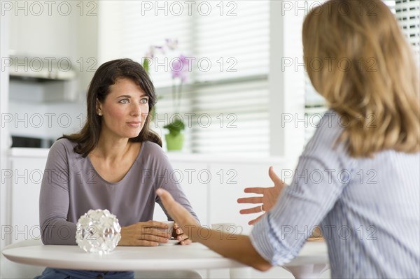 Caucasian women drinking coffee in kitchen