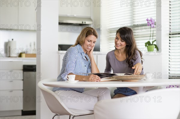 Caucasian women reading magazine in kitchen