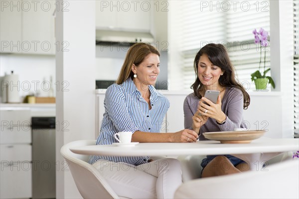 Caucasian women using cell phone in kitchen