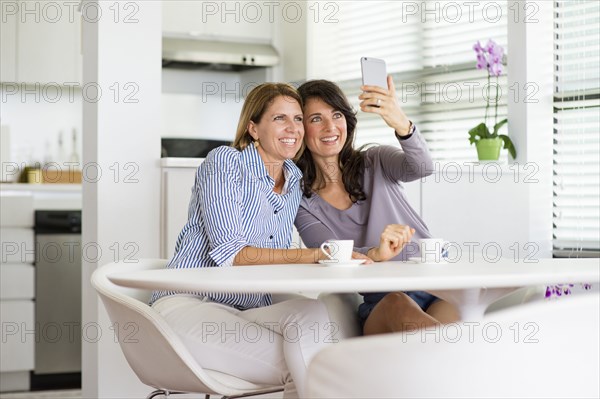 Caucasian women taking selfie in kitchen