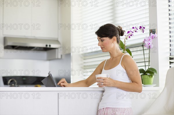 Caucasian woman using digital tablet in kitchen