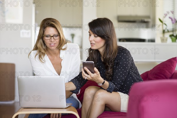 Caucasian women using cell phone on sofa