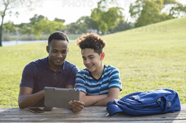 Father and son using digital tablet in park