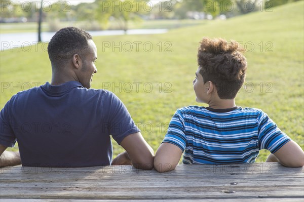 Father and son sitting at table in park