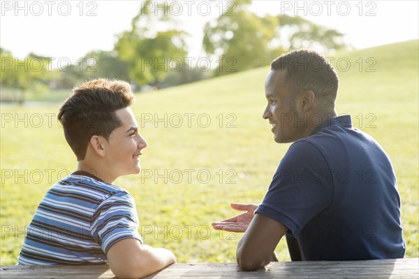Father and son talking at table in park