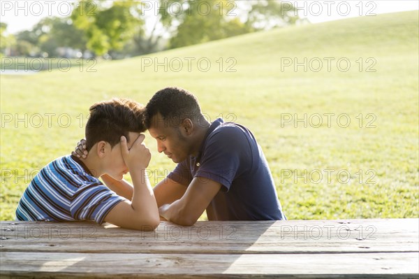 Father and son talking at table in park