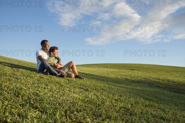 Father and son sitting in grass