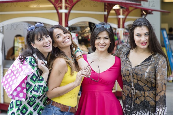 Smiling Hispanic women holding shopping bags