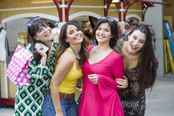 Smiling Hispanic women holding shopping bags