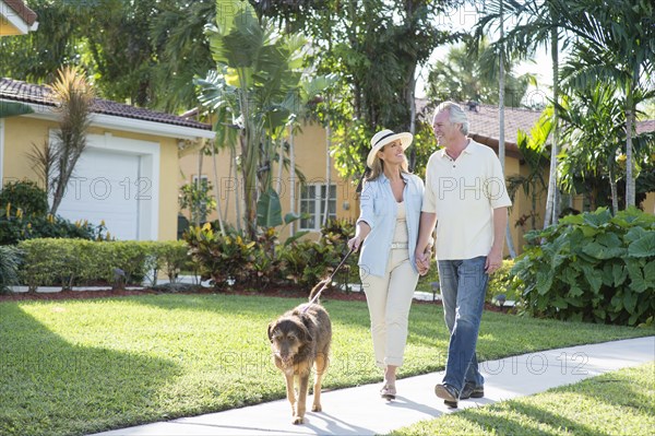 Caucasian couple walking dog in neighborhood