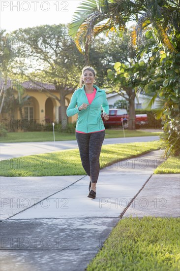 Caucasian woman jogging on sidewalk