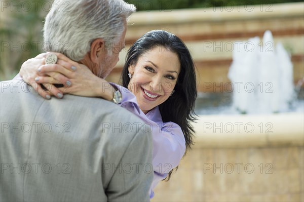 Caucasian couple hugging near fountain