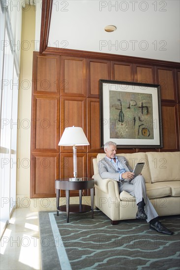 Caucasian man sitting on sofa using digital tablet