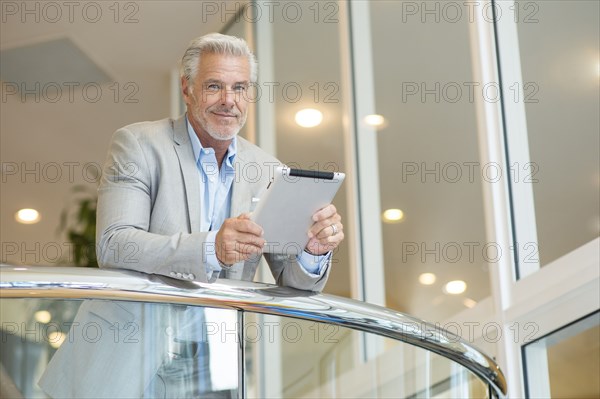 Caucasian man leaning on railing using digital tablet
