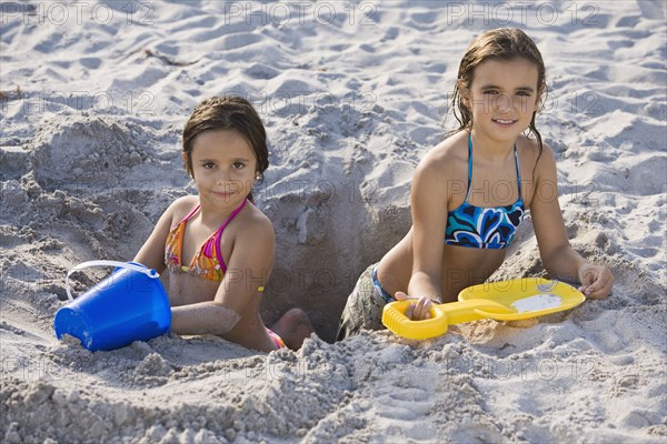 Hispanic girls digging in sand