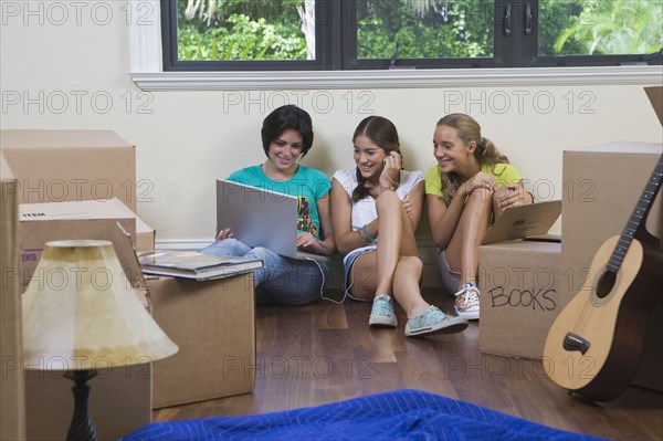 Hispanic teenage girls and woman using laptop