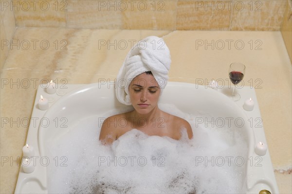 Hispanic woman relaxing in bubble bath