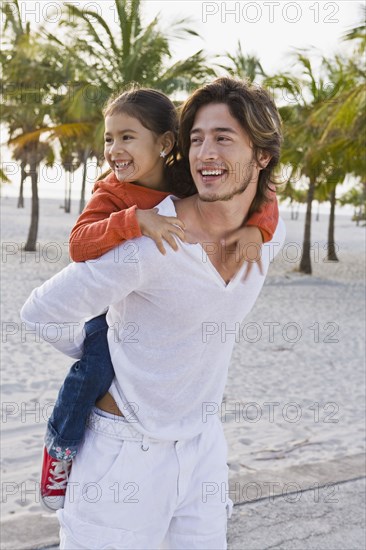 Hispanic father carrying daughter on back