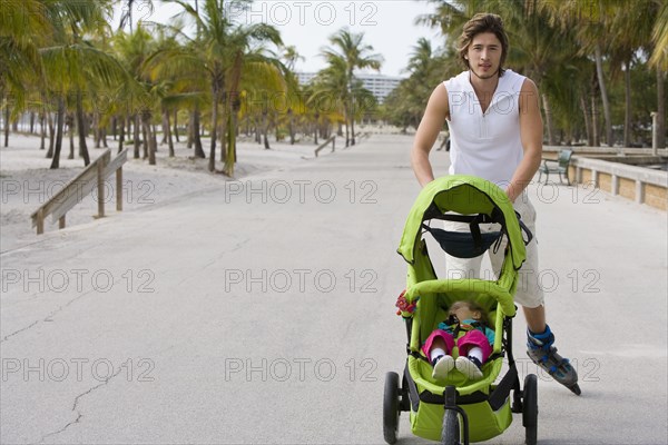 Hispanic man on roller blades pushing jogging stroller