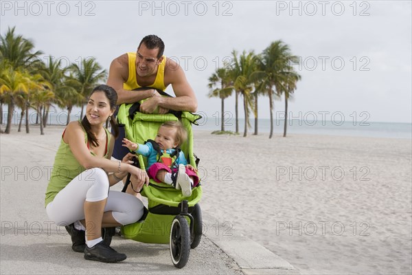 Hispanic couple stopping with baby in jogging stroller