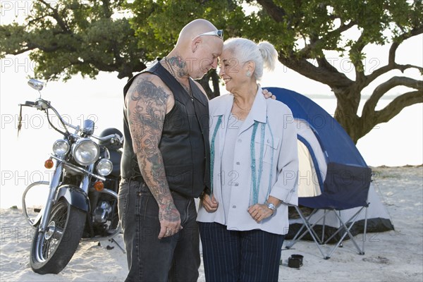 Mother and tattooed son camping at the beach